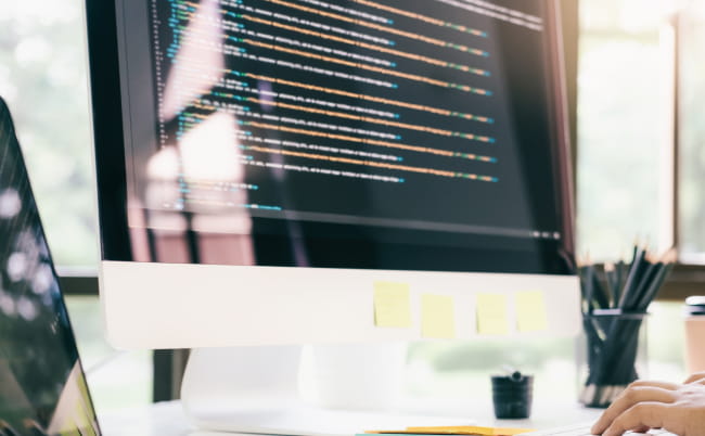 コードが表示されたモニターで作業する様子