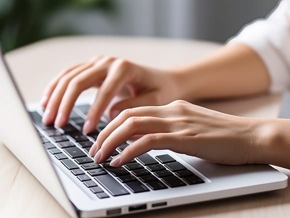ノートパソコンでタイピングする手元